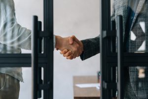 Dois empresários apertando as mãos em um escritório, representando um acordo comercial, como no modelo de franquia.