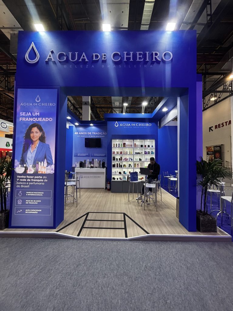 Estande da Água de Cheiro em evento de franquias, com destaque para convite a novos franqueados e exposição de produtos.